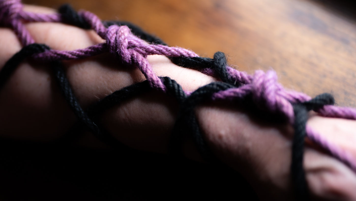 An arm laced in purple and black rope